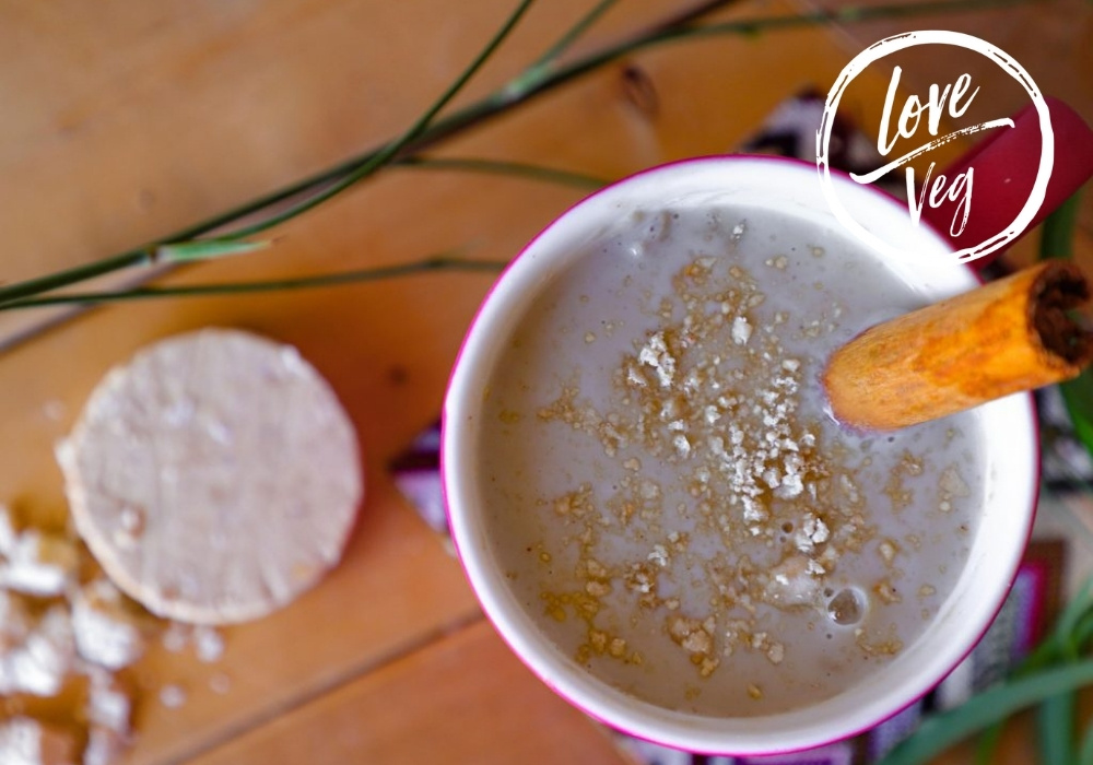 Atole de mazapán cremoso servido en una taza, con una raja de canela y migajas de mazapán a un lado.