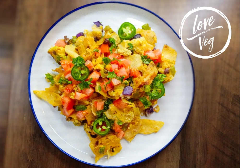 Migas Tex Mex preparadas con totopos crujientes, revuelto vegetal nutritivo, pico de gallo fresco, cilantro y jalapeños en un plato blanco.