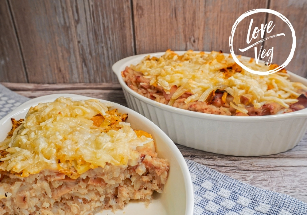 Fuente de cremoso arroz con palmito horneado y queso vegano derretido, sobre una mesa rústica.