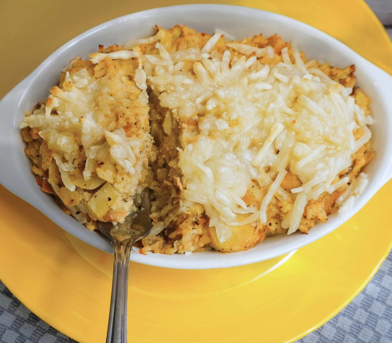 Fuente de cremoso arroz con palmito horneado y queso vegano derretido, sobre una mesa rústica.