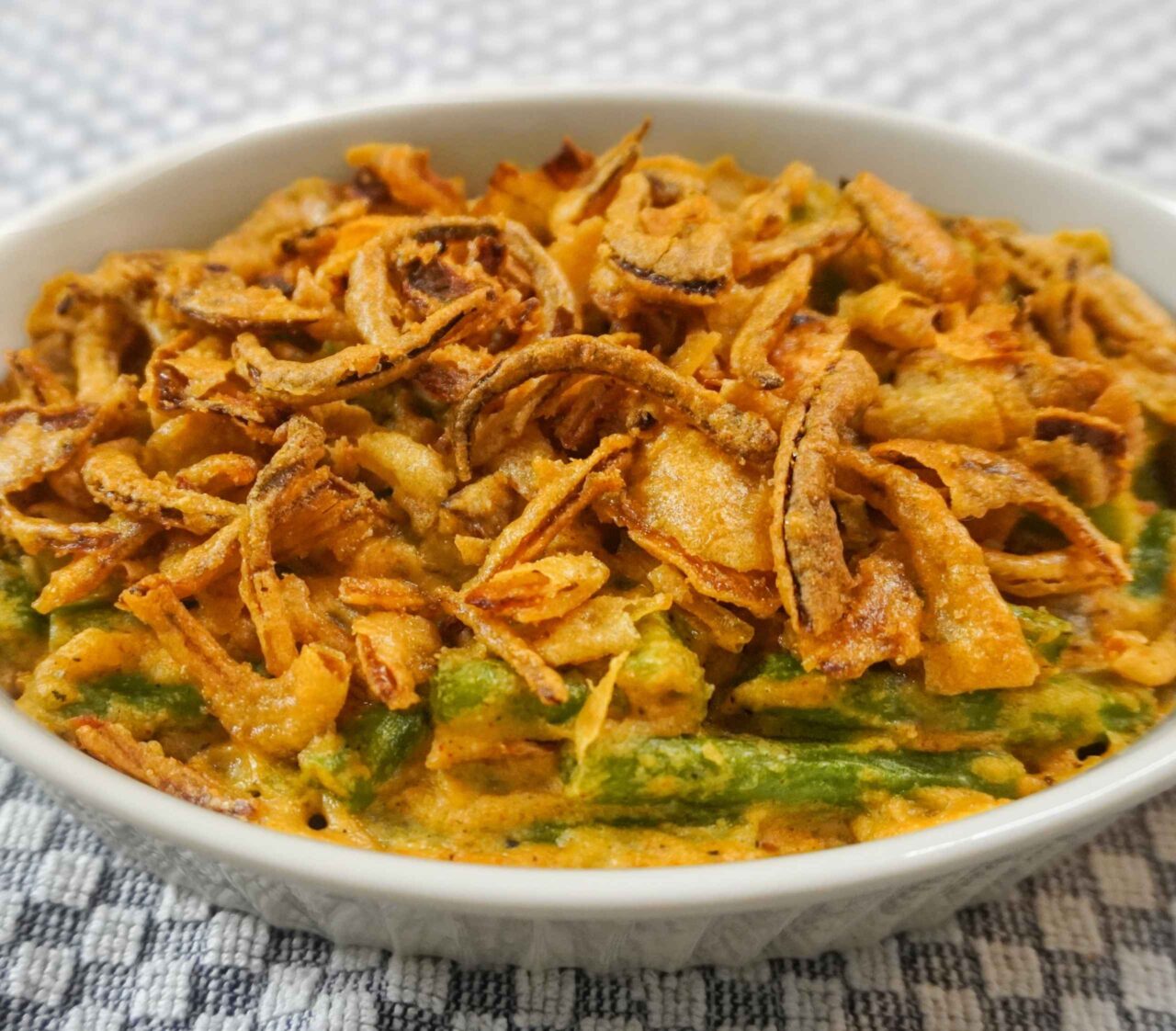 Cazuela vegana de ejotes con salsa cremosa y topping crujiente de cebolla, horneada al estilo latino.