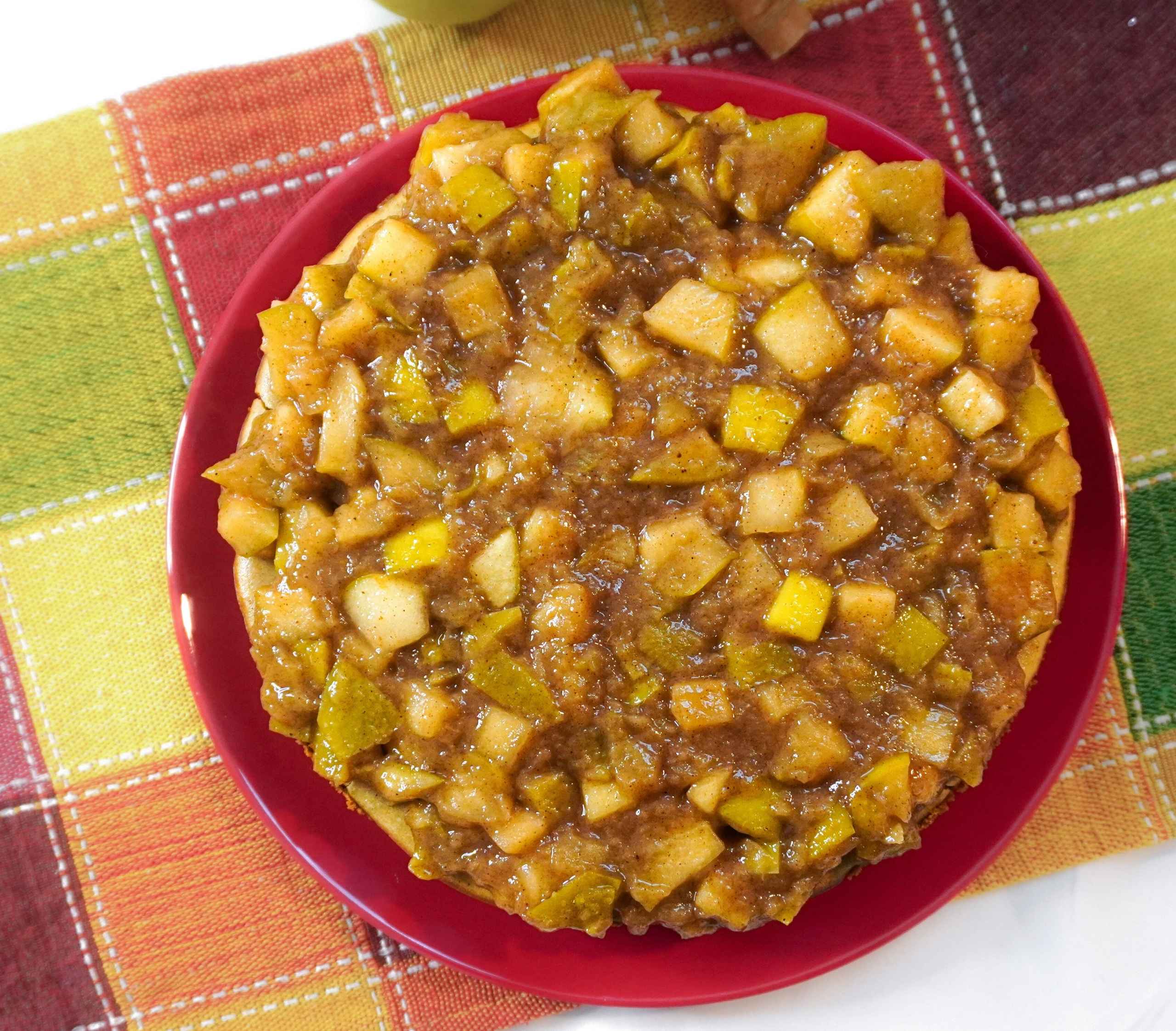 Cheesecake vegano de manzana caramelizada con canela y base de galleta, servido frío sobre un plato.