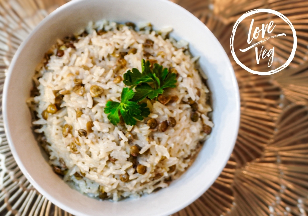 Arroz blanco cocido en leche de coco con lentejas tiernas, servido en un plato hondo y decorado con cilantro fresco.