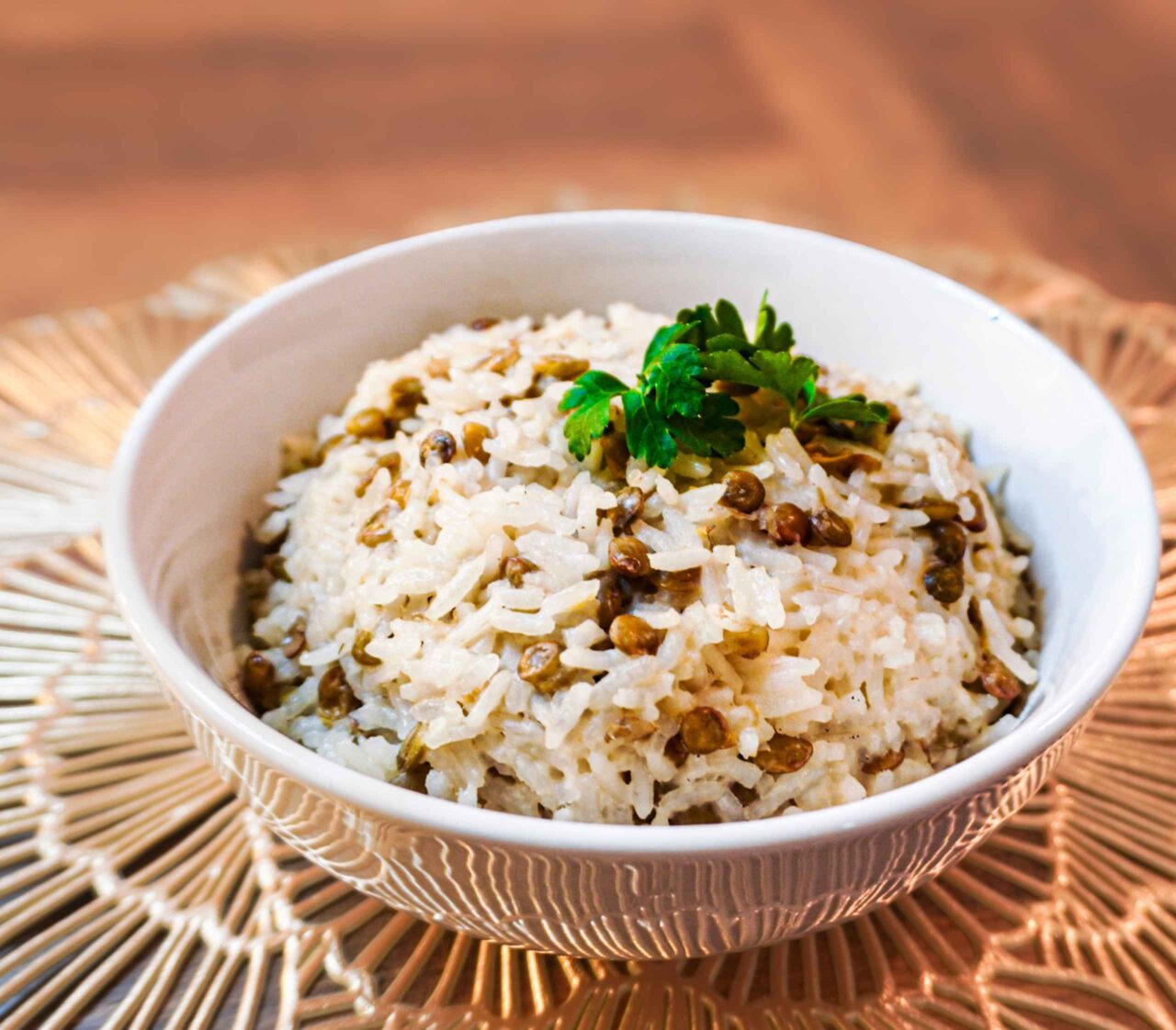 Arroz blanco cocido en leche de coco con lentejas tiernas, servido en un plato hondo y decorado con cilantro fresco.