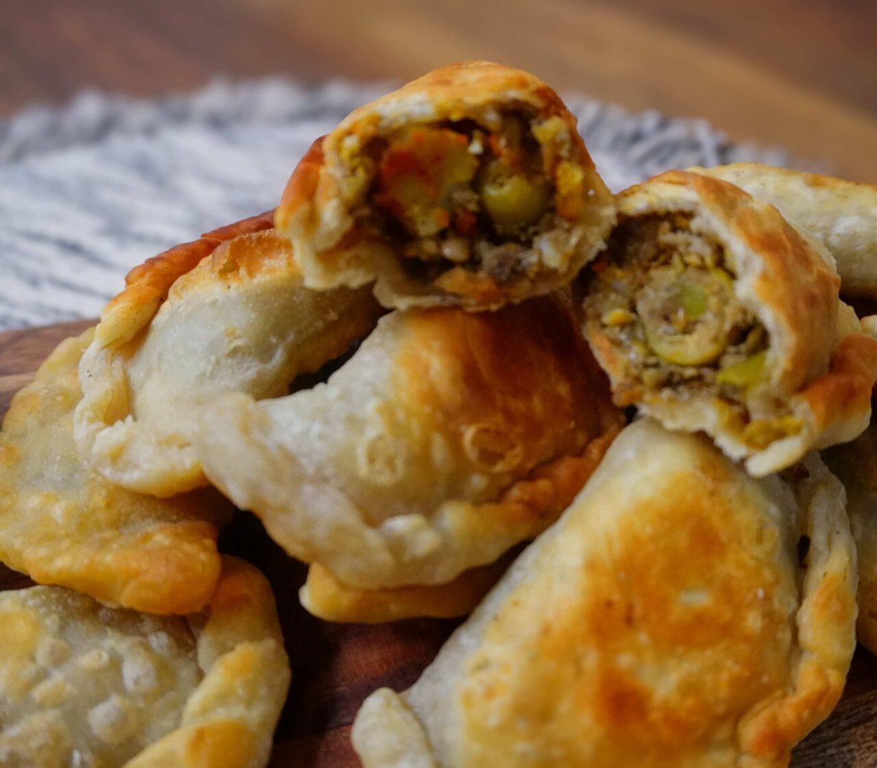 Empanadillas veganas puertorriqueñas fritas, servidas en un plato con salsa picante.