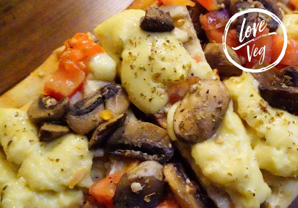 Queso vegano elástico y derretible sobre un pan plano tipo flatbread, mostrando una textura suave y elástica.