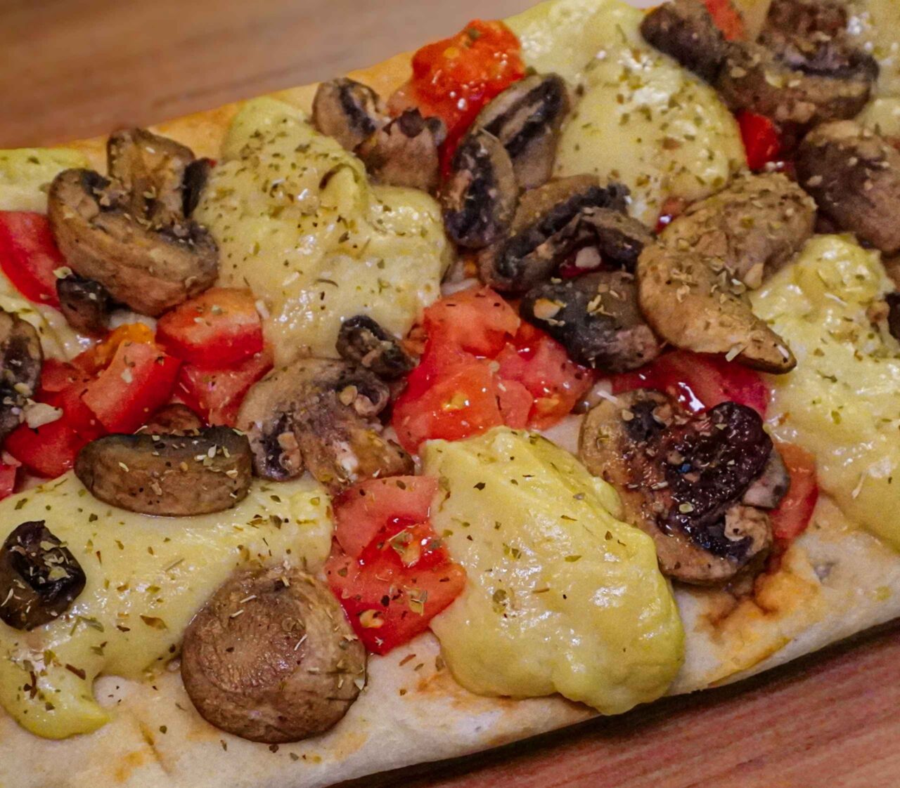Queso vegano elástico y derretible sobre un pan plano tipo flatbread, mostrando una textura suave y elástica.