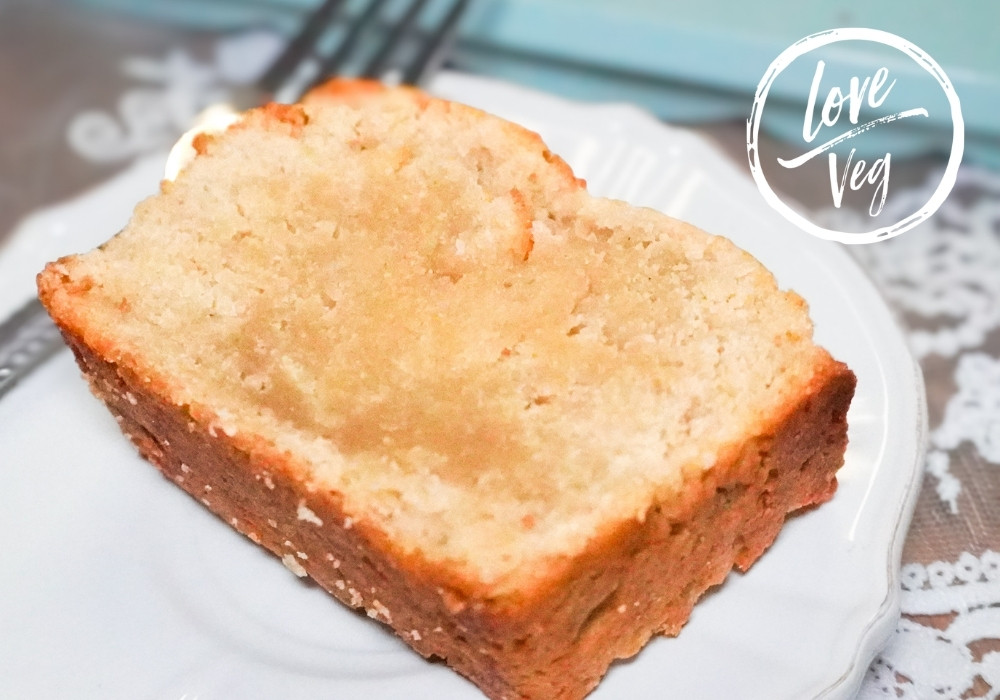 Primer plano de una rebanada de panqué mexicano vegano dorado y firme sobre un plato blanco. La miga se ve densa, suave y perfecta para el desayuno.