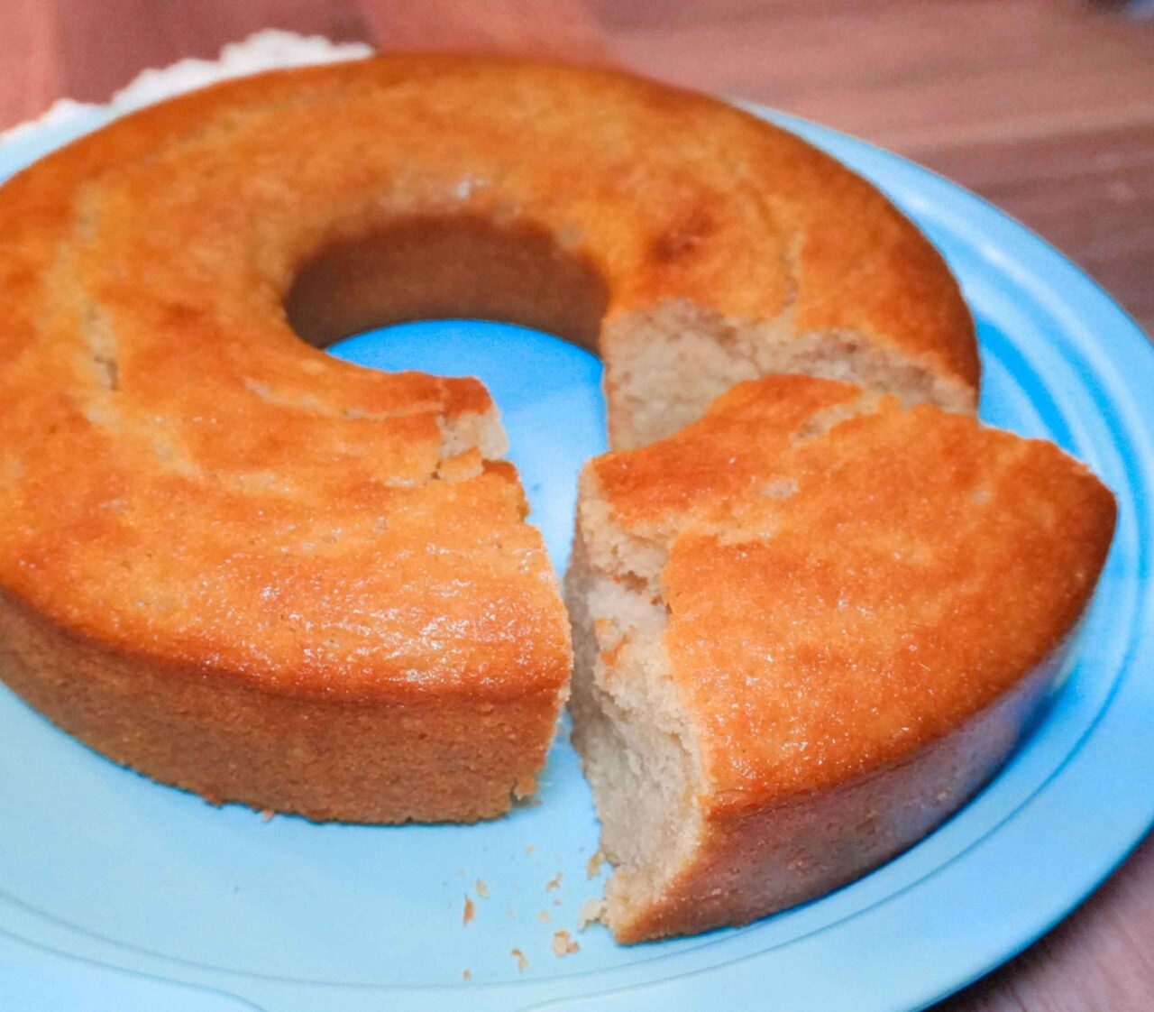 Queque seco vegano de naranja y vainilla con textura esponjosa y miga porosa, servido en un plato azul. Receta de repostería basada en plantas con aquafaba.