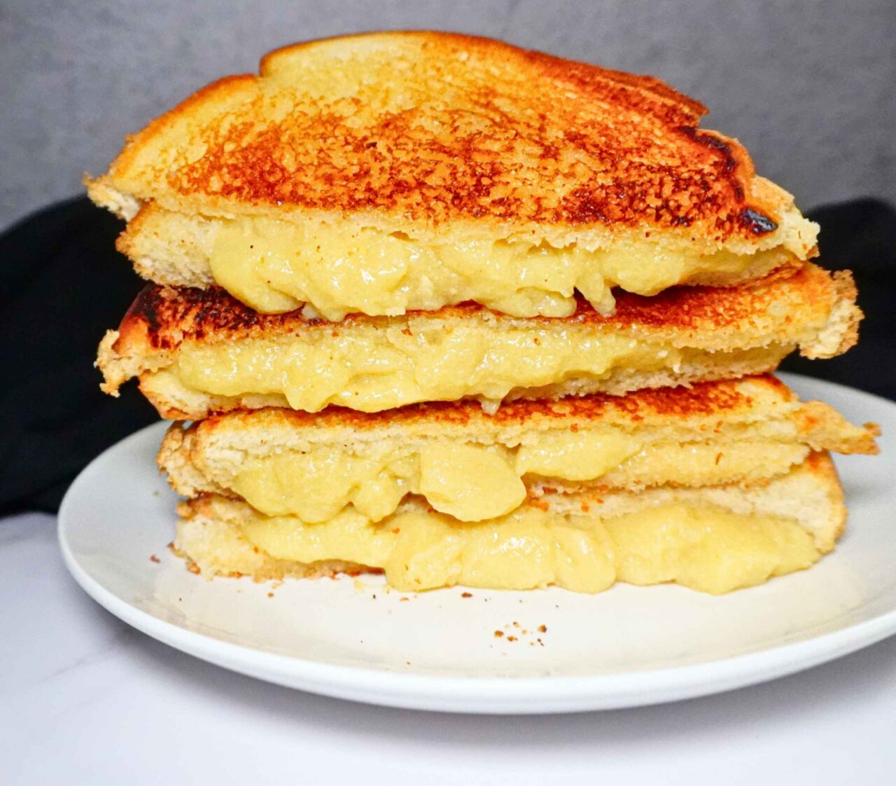 Sándwich de queso vegano derretido hecho con leche de avena y pan tostado dorado en una sartén.